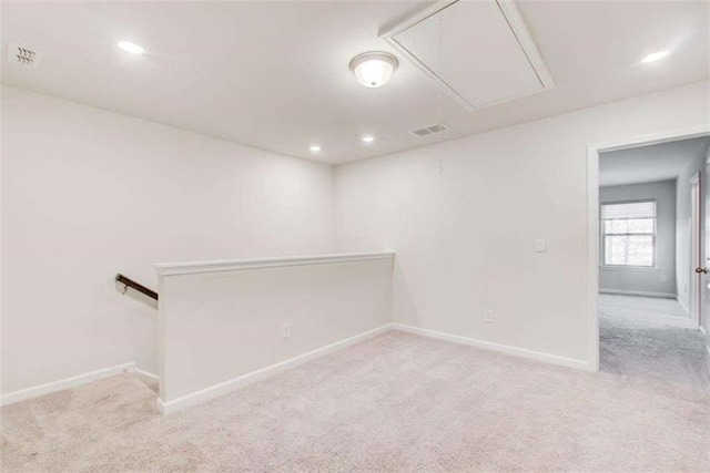 carpeted empty room featuring attic access, visible vents, and baseboards