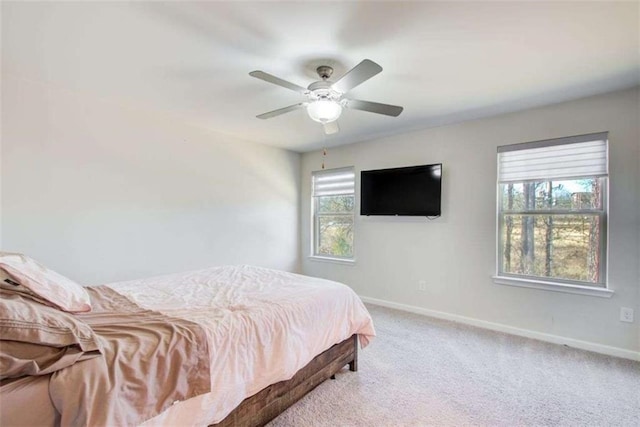 carpeted bedroom featuring a ceiling fan, multiple windows, and baseboards