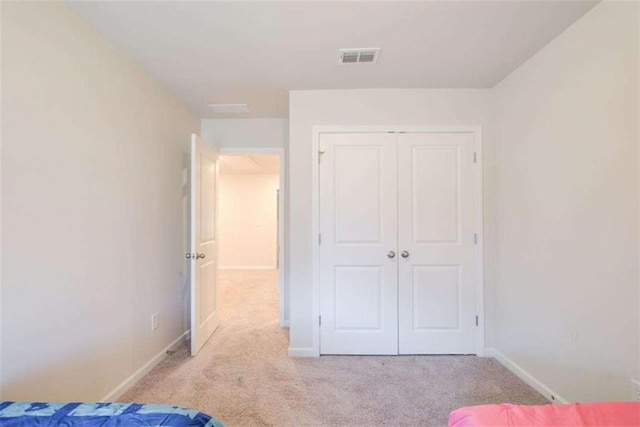 unfurnished bedroom with a closet, carpet flooring, visible vents, and baseboards