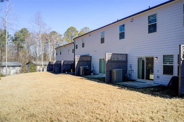 rear view of property featuring central air condition unit and a lawn