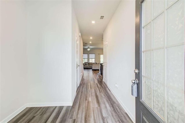 hall featuring visible vents, baseboards, wood finished floors, and recessed lighting