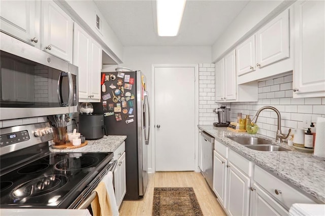 1303 Wingate Way, Atlanta, GA 30350 - kitchen featuring appliances with stainless steel finishes, a sink, light wood finished floors, white cabinetry, and backsplash