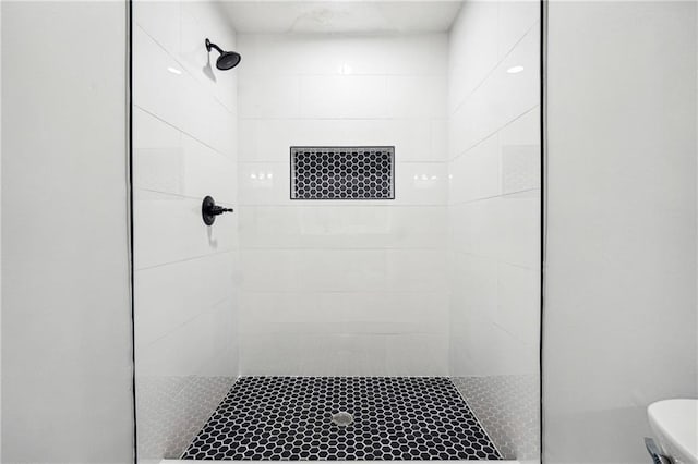 bathroom featuring tiled shower and toilet