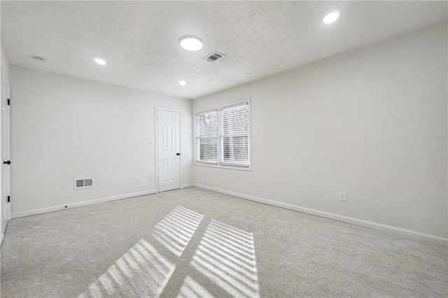 unfurnished room with light carpet and a textured ceiling