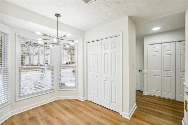 unfurnished dining area featuring a chandelier, wood-type flooring, and a textured ceiling