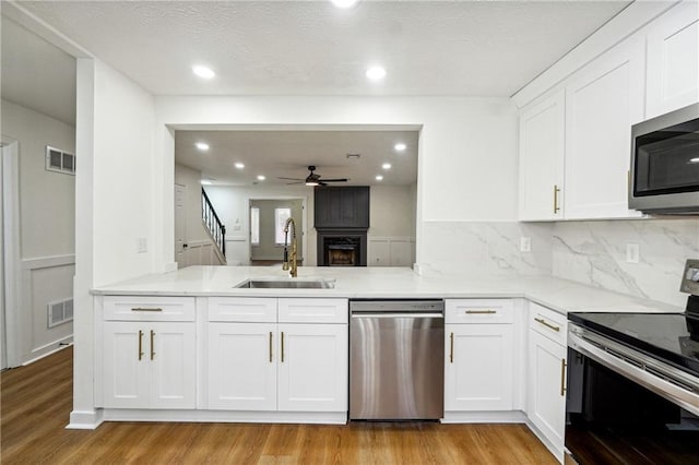 kitchen featuring stainless steel appliances, ceiling fan, sink, light hardwood / wood-style flooring, and white cabinets