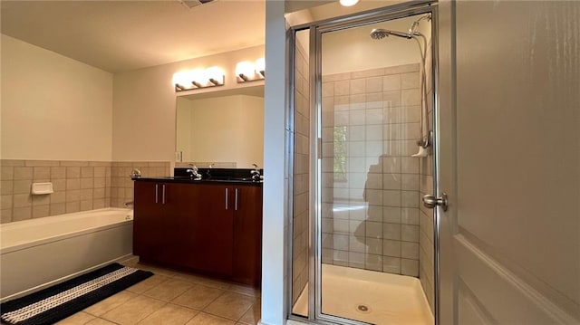 bathroom with tile patterned floors, vanity, tile walls, and shower with separate bathtub