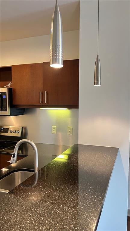 kitchen with dark stone countertops, sink, and stainless steel appliances