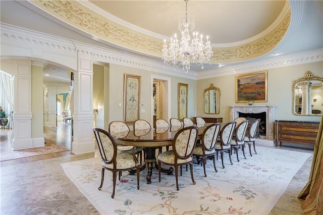 dining area with crown molding, a tray ceiling, a chandelier, and decorative columns