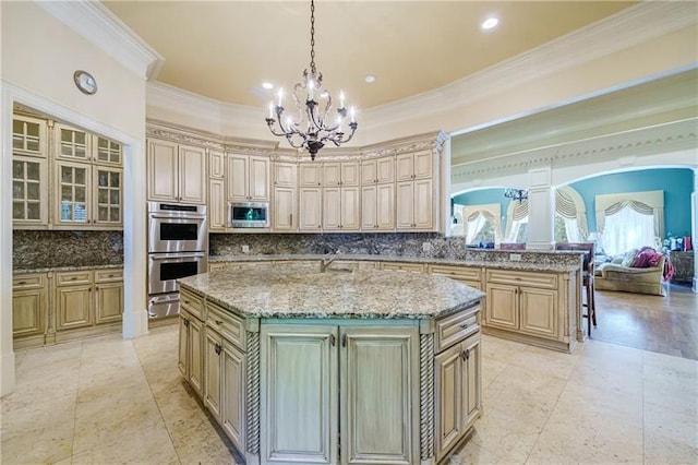 kitchen with light stone countertops, decorative light fixtures, stainless steel appliances, tasteful backsplash, and a center island with sink