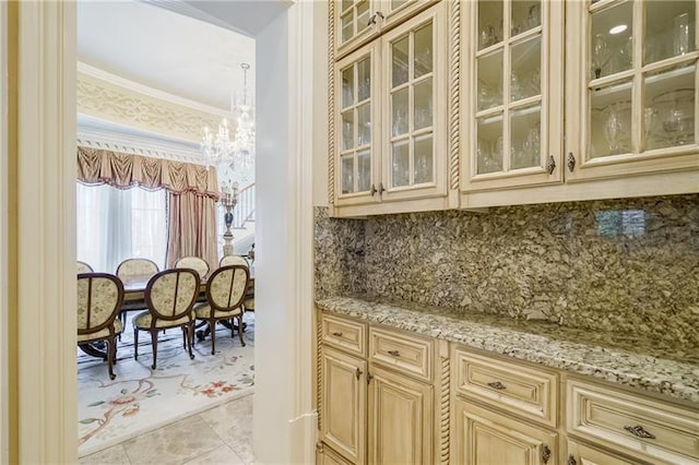 bar with tasteful backsplash, a notable chandelier, light tile patterned flooring, light stone countertops, and crown molding