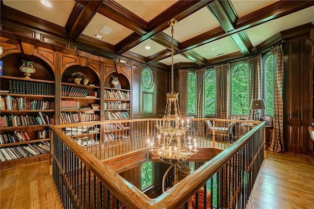 interior space with hardwood / wood-style flooring, beam ceiling, a notable chandelier, and coffered ceiling