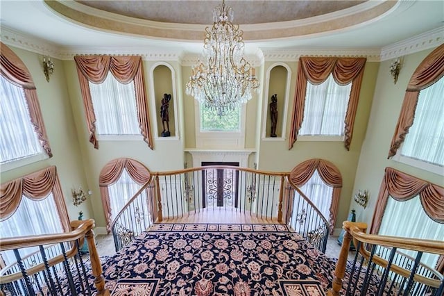 stairway featuring a healthy amount of sunlight, a chandelier, crown molding, and a tray ceiling