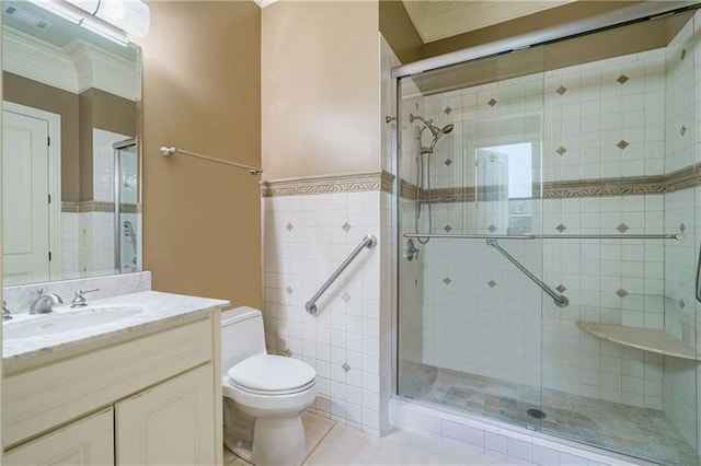 bathroom featuring tile patterned floors, vanity, tile walls, toilet, and a shower with shower door