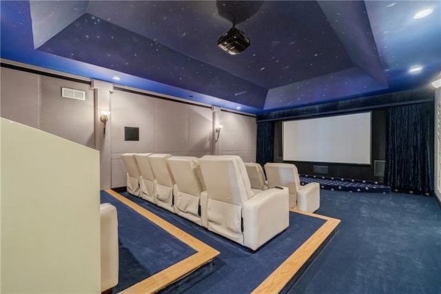 home theater featuring dark colored carpet and a tray ceiling