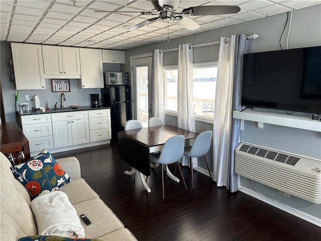 kitchen featuring sink, white cabinetry, dark hardwood / wood-style flooring, a wall unit AC, and ceiling fan