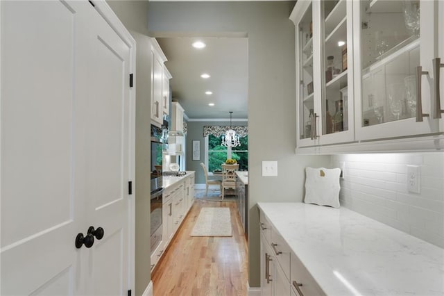 bar area with light wood-style flooring, decorative backsplash, recessed lighting, crown molding, and a chandelier