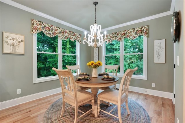 dining area featuring a chandelier, light wood-style flooring, baseboards, and crown molding