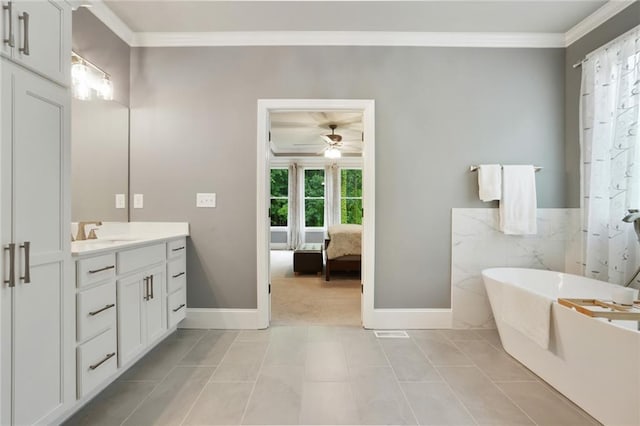 bathroom with crown molding, ceiling fan, vanity, a soaking tub, and baseboards