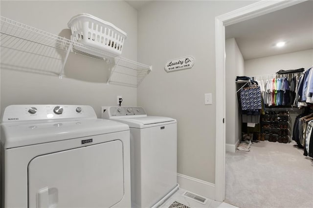 clothes washing area with washer and dryer, baseboards, and carpet