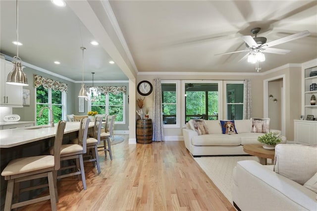 living room with light wood finished floors, recessed lighting, crown molding, ceiling fan, and baseboards