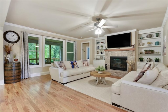 living area with a ceiling fan, light wood-style flooring, baseboards, a fireplace, and crown molding