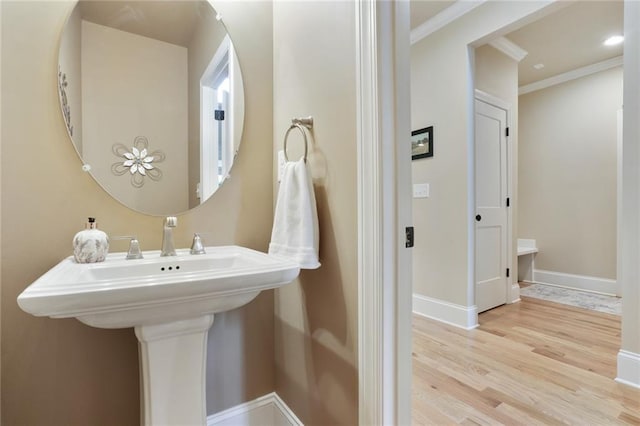 bathroom featuring crown molding, wood finished floors, and baseboards