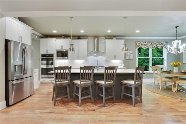 kitchen featuring appliances with stainless steel finishes, wall chimney range hood, light wood-style flooring, white cabinetry, and recessed lighting