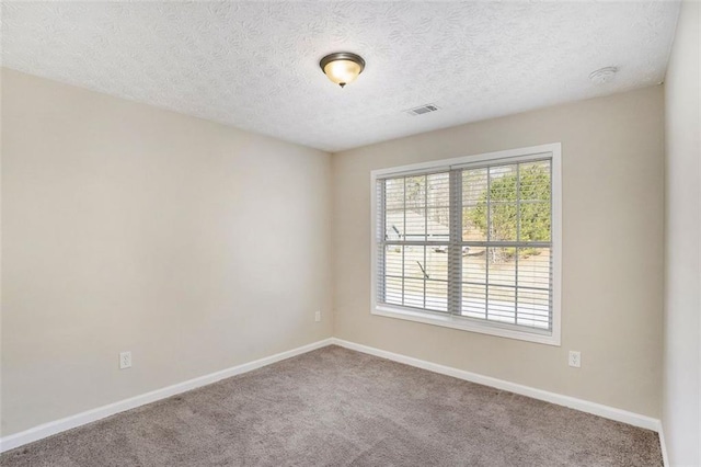 carpeted spare room with visible vents, a textured ceiling, and baseboards