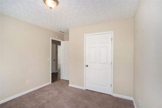 unfurnished bedroom with carpet, a textured ceiling, and baseboards