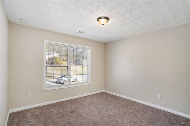 spare room featuring carpet, visible vents, a textured ceiling, and baseboards