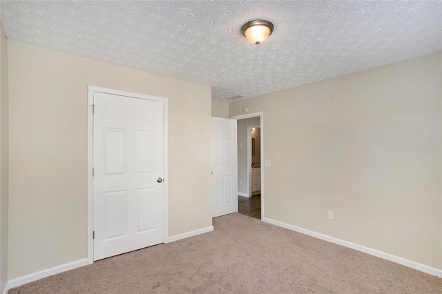 unfurnished bedroom with a textured ceiling, carpet, and baseboards