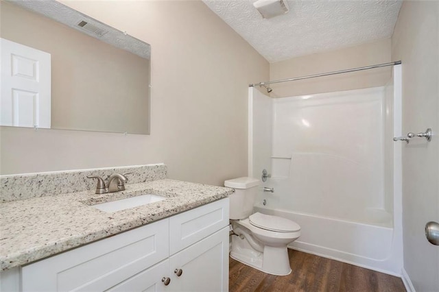 bathroom featuring toilet, wood finished floors, a textured ceiling, vanity, and shower / washtub combination