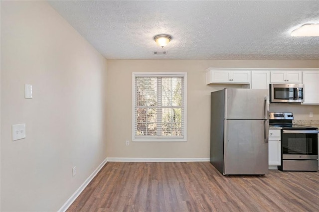 kitchen with baseboards, appliances with stainless steel finishes, white cabinets, and wood finished floors