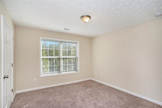 carpeted empty room with visible vents, a textured ceiling, and baseboards