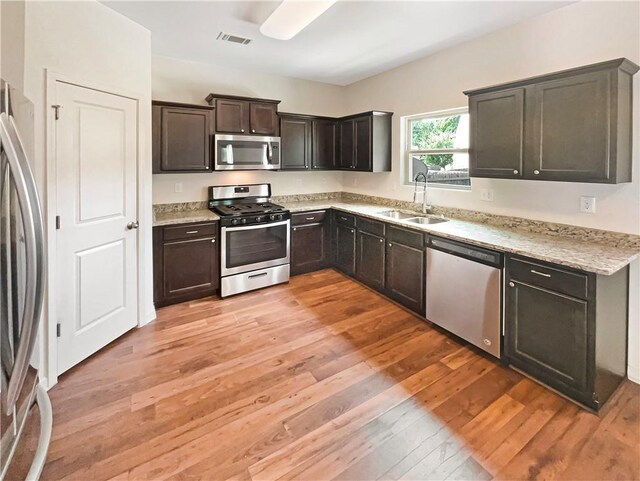 kitchen with light hardwood / wood-style flooring, appliances with stainless steel finishes, dark brown cabinets, and sink