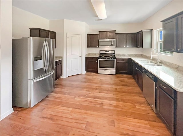 kitchen featuring appliances with stainless steel finishes, dark brown cabinets, sink, and light hardwood / wood-style flooring