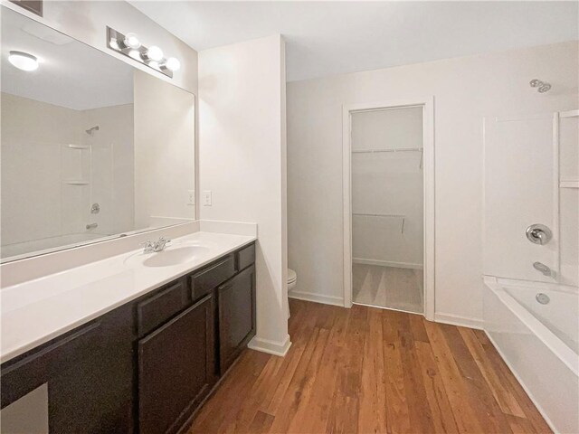 full bathroom with tub / shower combination, vanity, toilet, and wood-type flooring