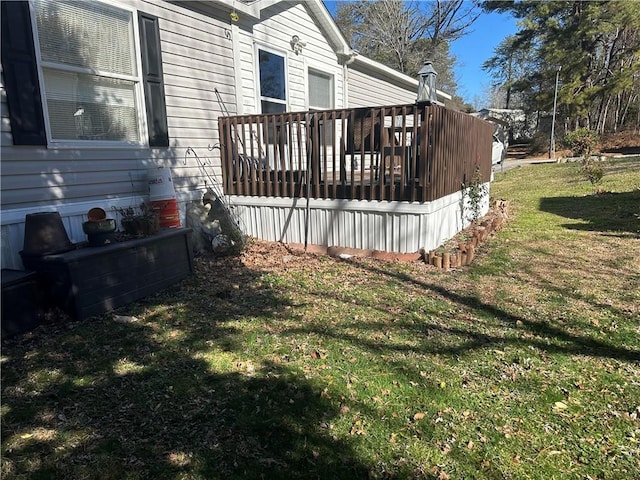 view of side of home with a deck and a lawn