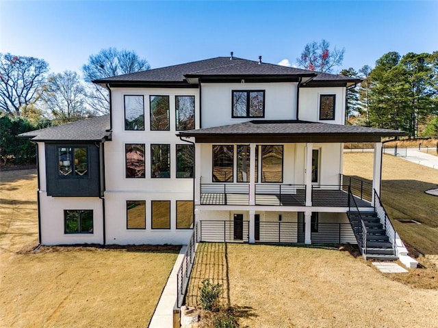 rear view of property featuring stucco siding, a lawn, a porch, and stairway