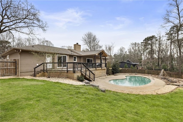 rear view of house with a lawn, a chimney, a fenced backyard, and a fenced in pool