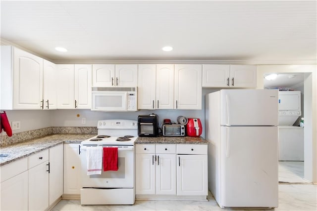 kitchen with light stone countertops, white cabinetry, stacked washer / dryer, and white appliances