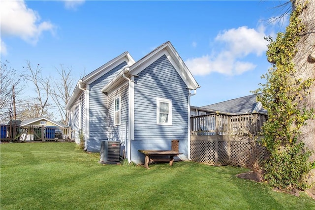 back of house with cooling unit, a yard, and a wooden deck