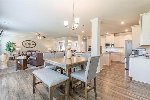 dining room featuring ceiling fan with notable chandelier and light wood-type flooring