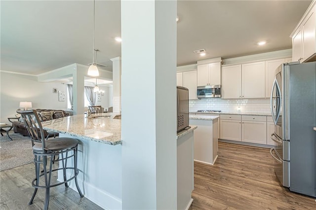 kitchen featuring a kitchen bar, light hardwood / wood-style floors, stainless steel appliances, and white cabinets