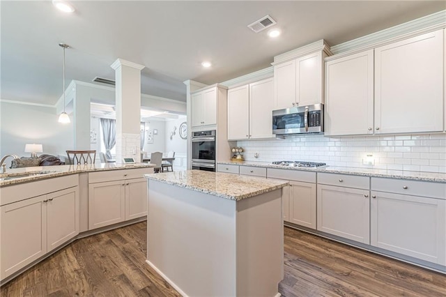 kitchen featuring ornamental molding, stainless steel appliances, dark hardwood / wood-style floors, and light stone counters