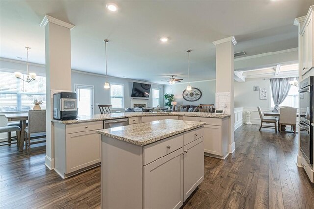 kitchen featuring hanging light fixtures, ceiling fan with notable chandelier, dark wood-type flooring, and a center island