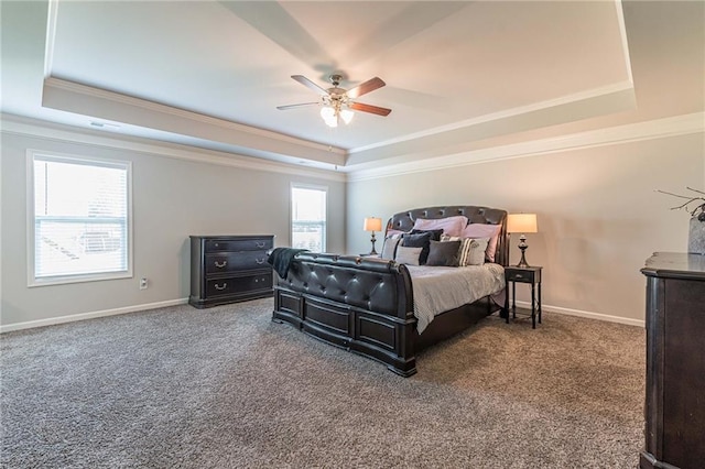 bedroom with dark colored carpet, ceiling fan, a tray ceiling, and multiple windows