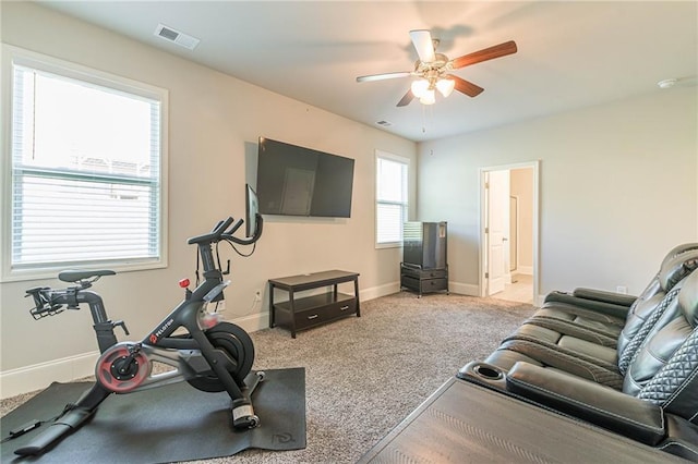 workout area featuring ceiling fan, plenty of natural light, and light carpet