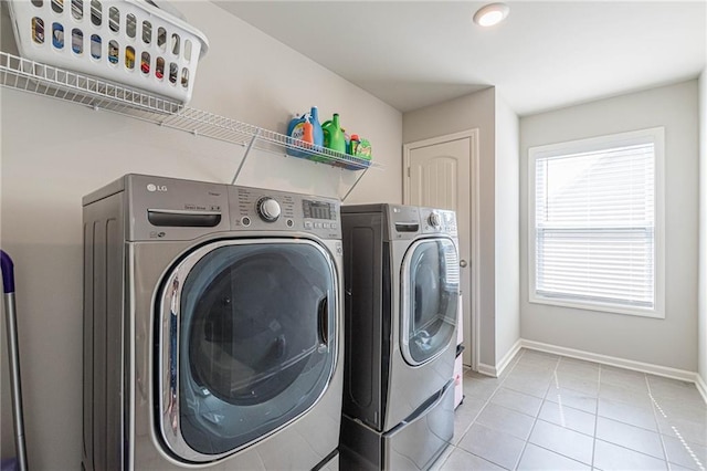 laundry area with light tile flooring and washing machine and dryer